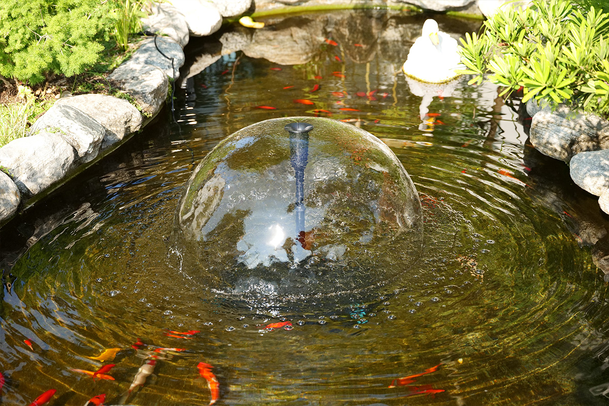 Poposoap Solar fountain producing a smooth dome water feature, adding movement and aeration to a garden pond.