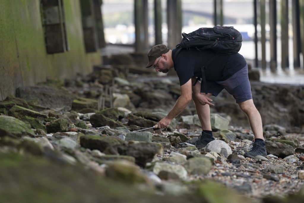 A man searches for an antique from the Thames River bed after the water retreats in London, United Kingdom