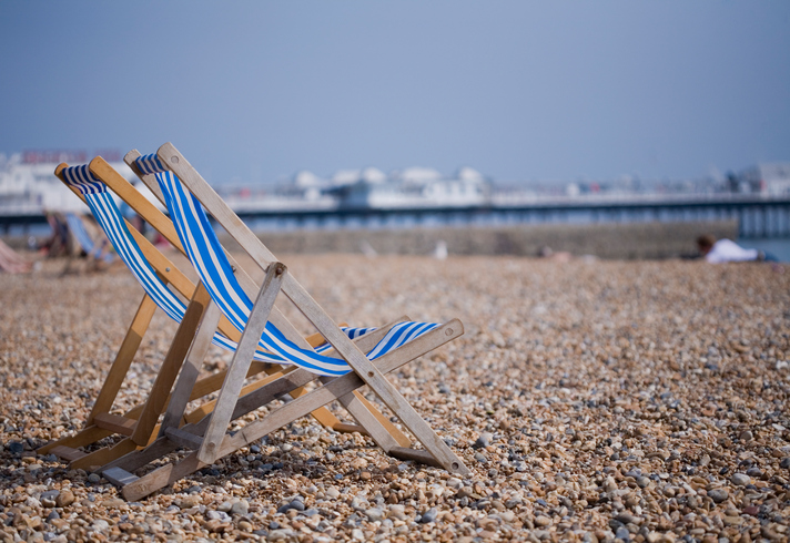 Two blue and white deckchairs on Brighton pebble beach, UK