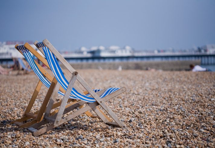 Two blue and white deckchairs on Brighton pebble beach, UK Two blue and white deckchairs on Brighton pebble beach, UK