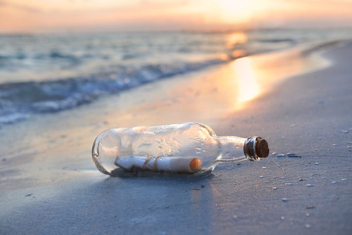 Message in a glass bottle on a beach at sunset Message in a bottle resting on shore during sunset