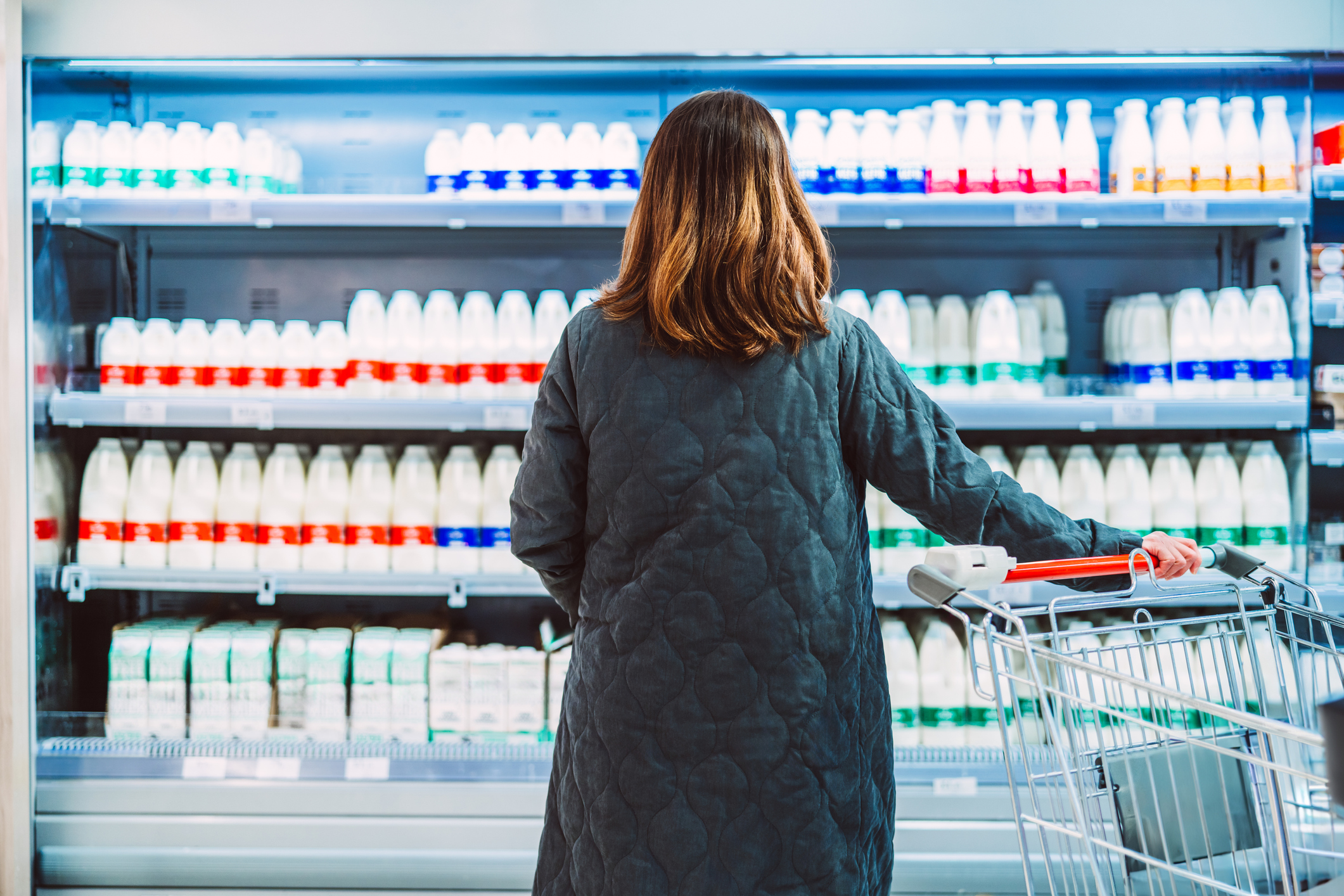 A rear view shot of a woman buying milk from a supermarket
