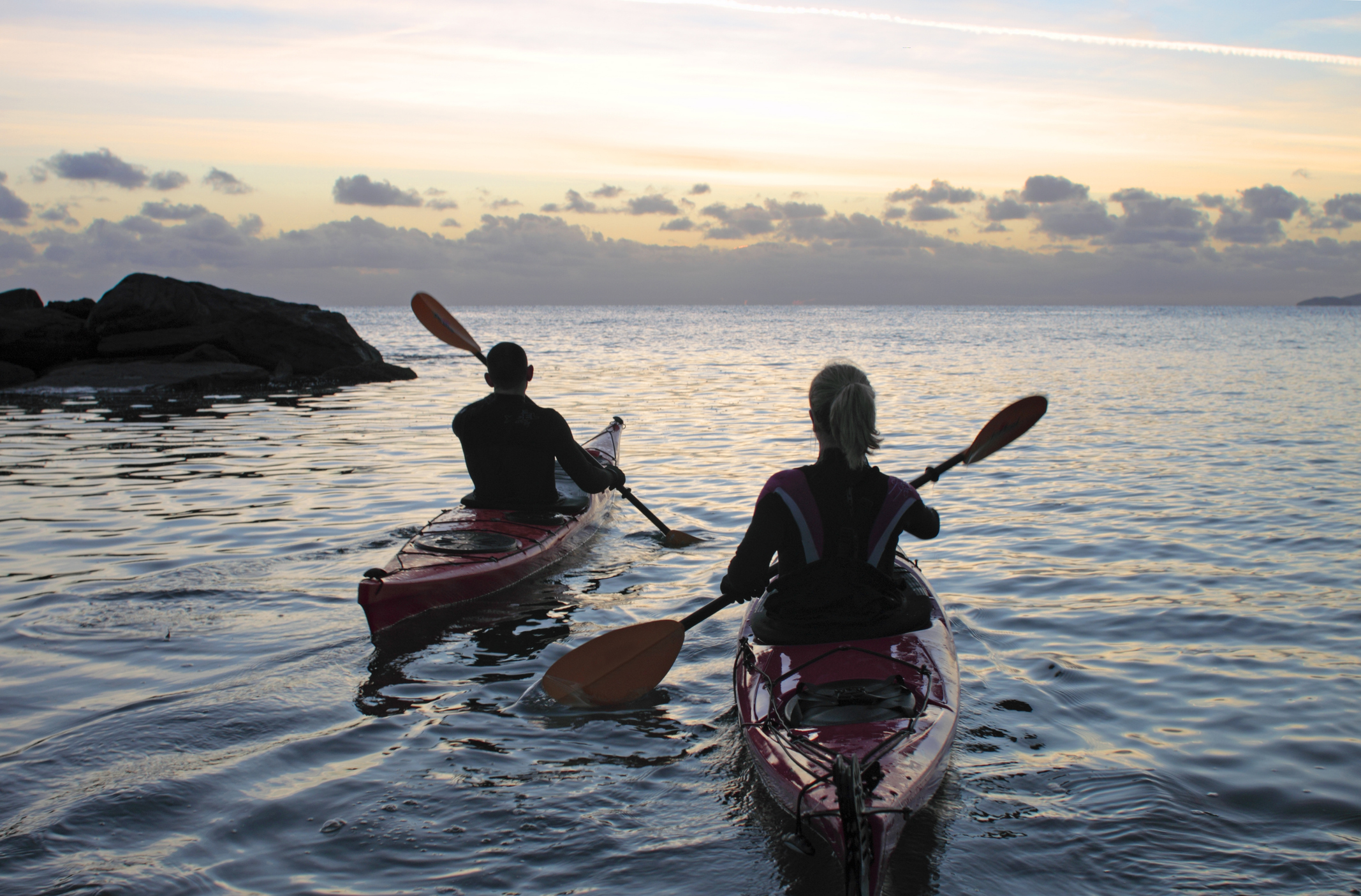 Two people kayaking in the sea late in the evening