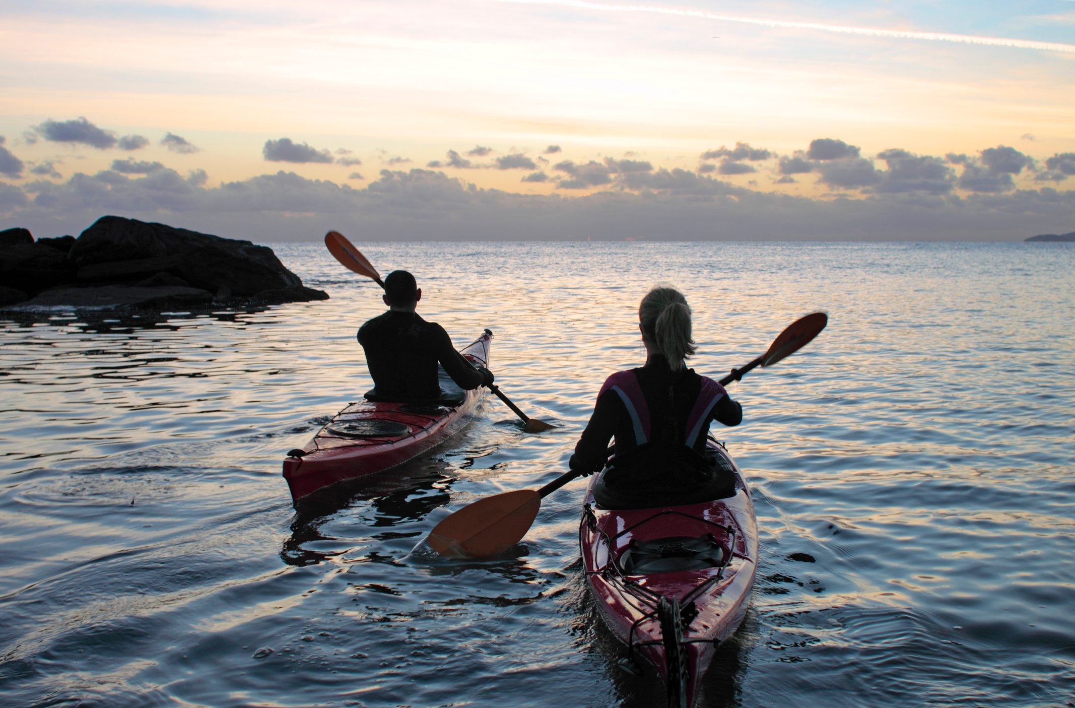 Two people kayaking in the sea late in the evening