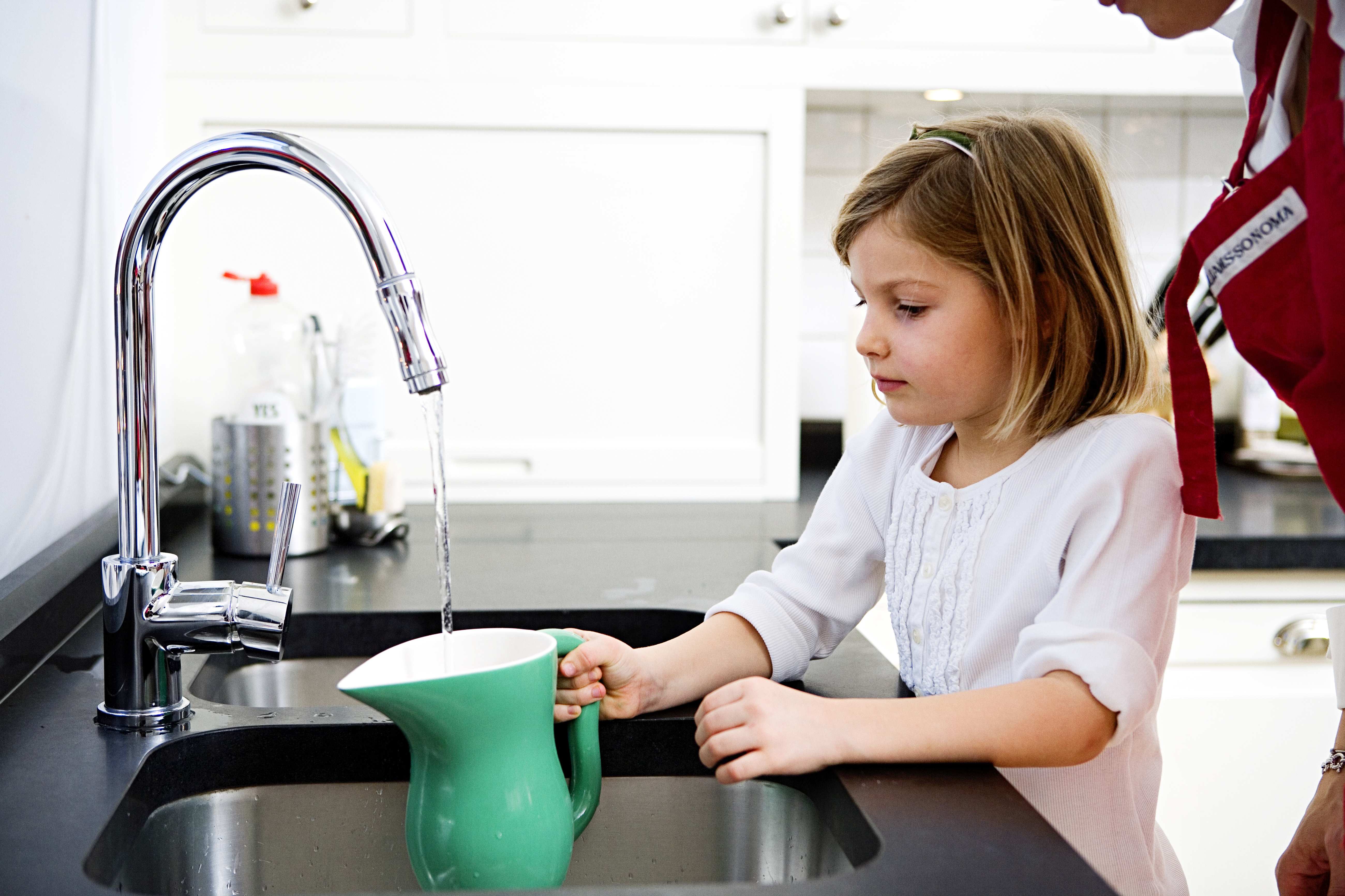 Filling a jug with water A girl filling a pitcher with water