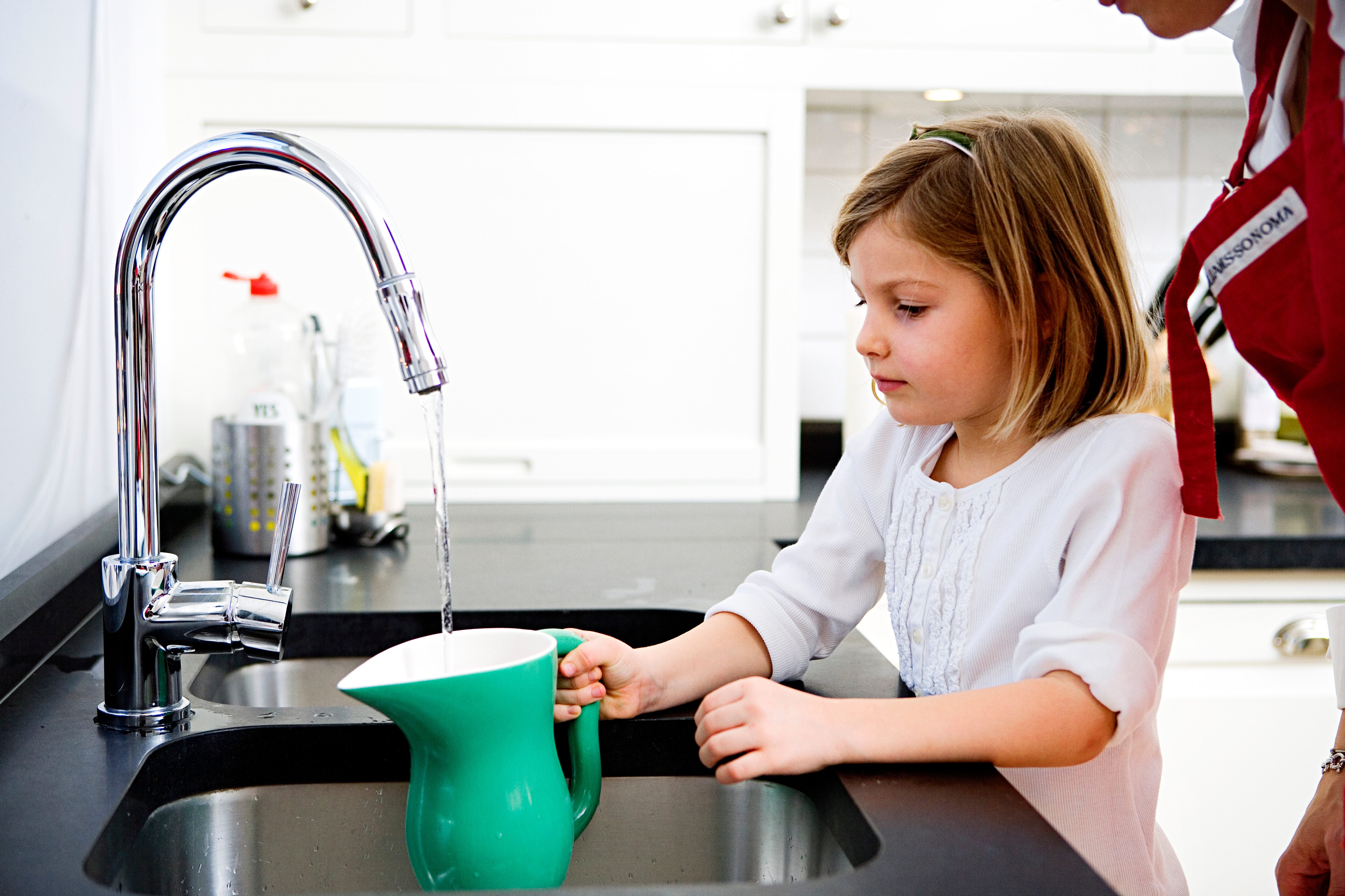 Filling a jug with water A girl filling a pitcher with water