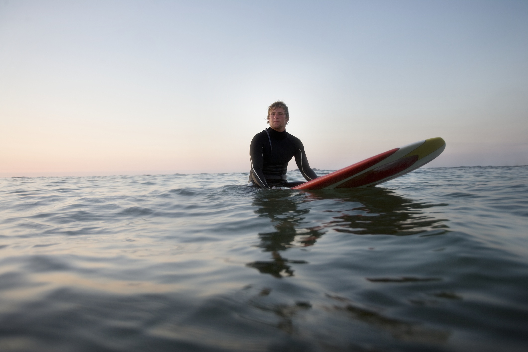 A person sat on a surfboard looking out to sea
