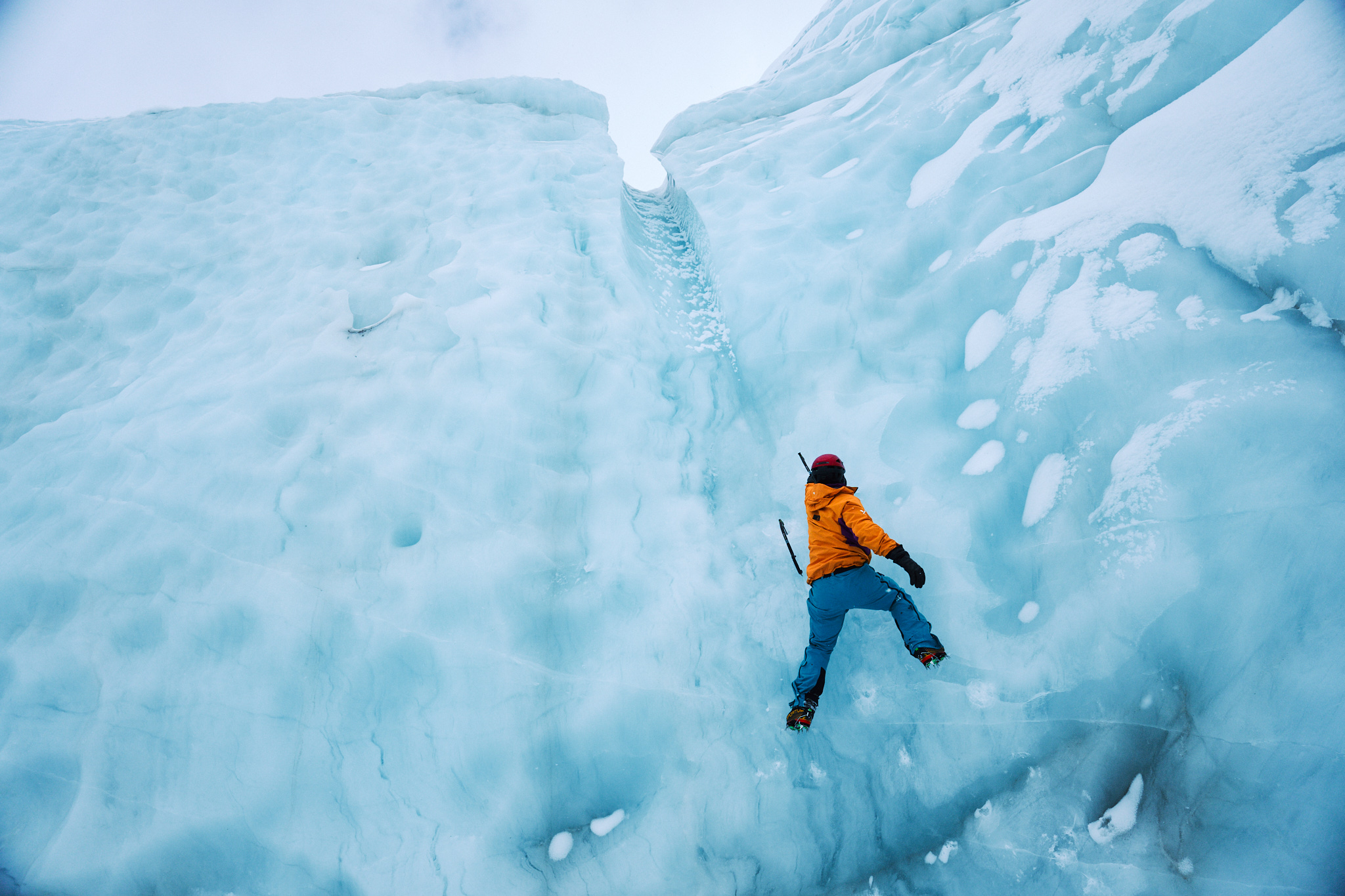 A man climbing up a mountain of ice.