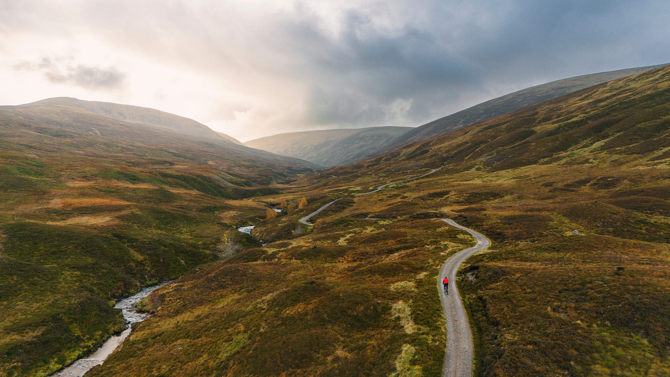 Wide landscape shot of a cyclist on a gravel trail in the mountains in the Cairngorms