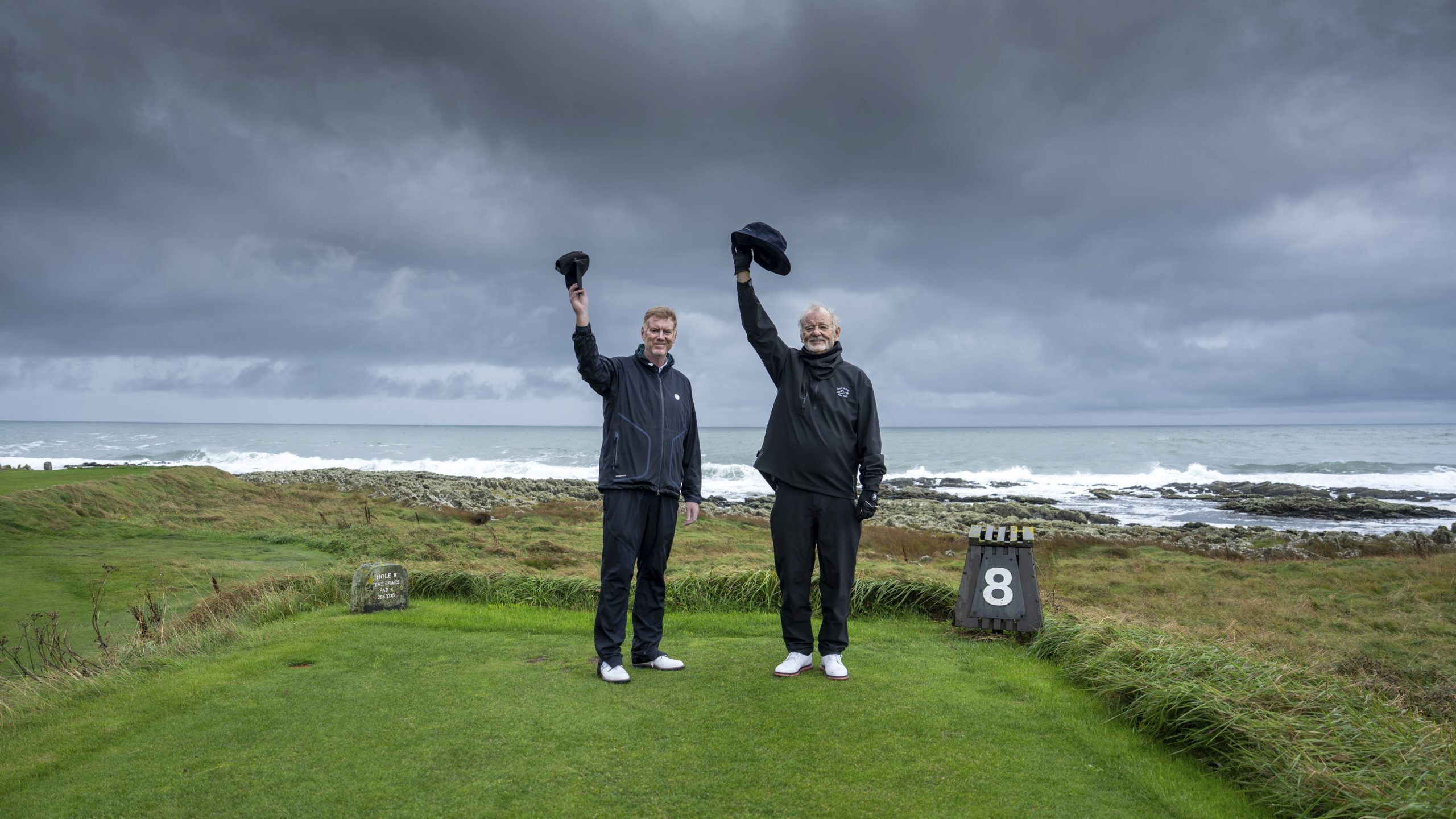 Bill Murray waving a hat while stood on a golf course