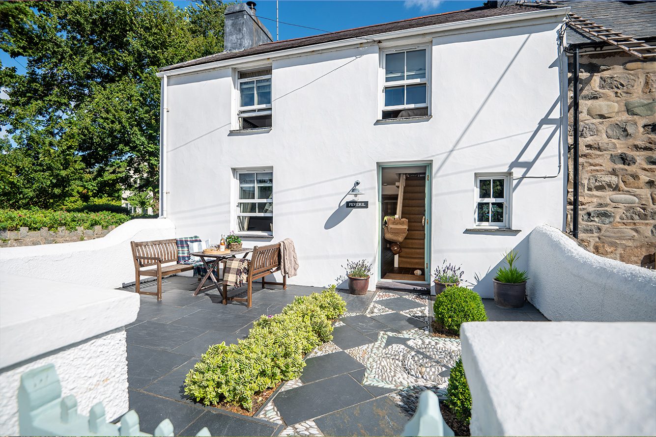 White two-story cottage with sunny front garden