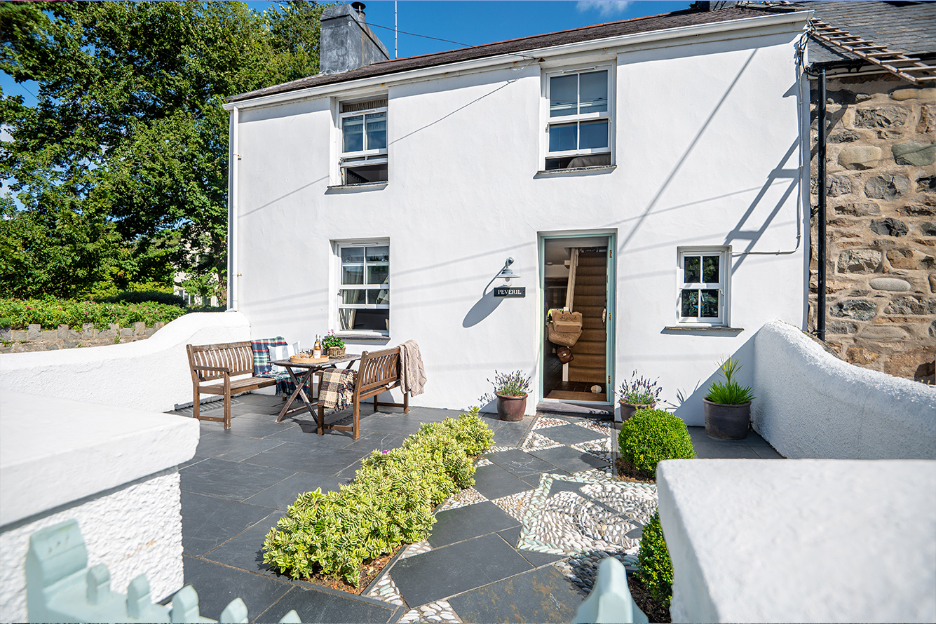 White two-story cottage with sunny front garden