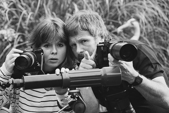 English conservationist and actor Bill Oddie watching birds with his wife Laura, 21st June 1985. Black and white photo of the pair close up with cameras