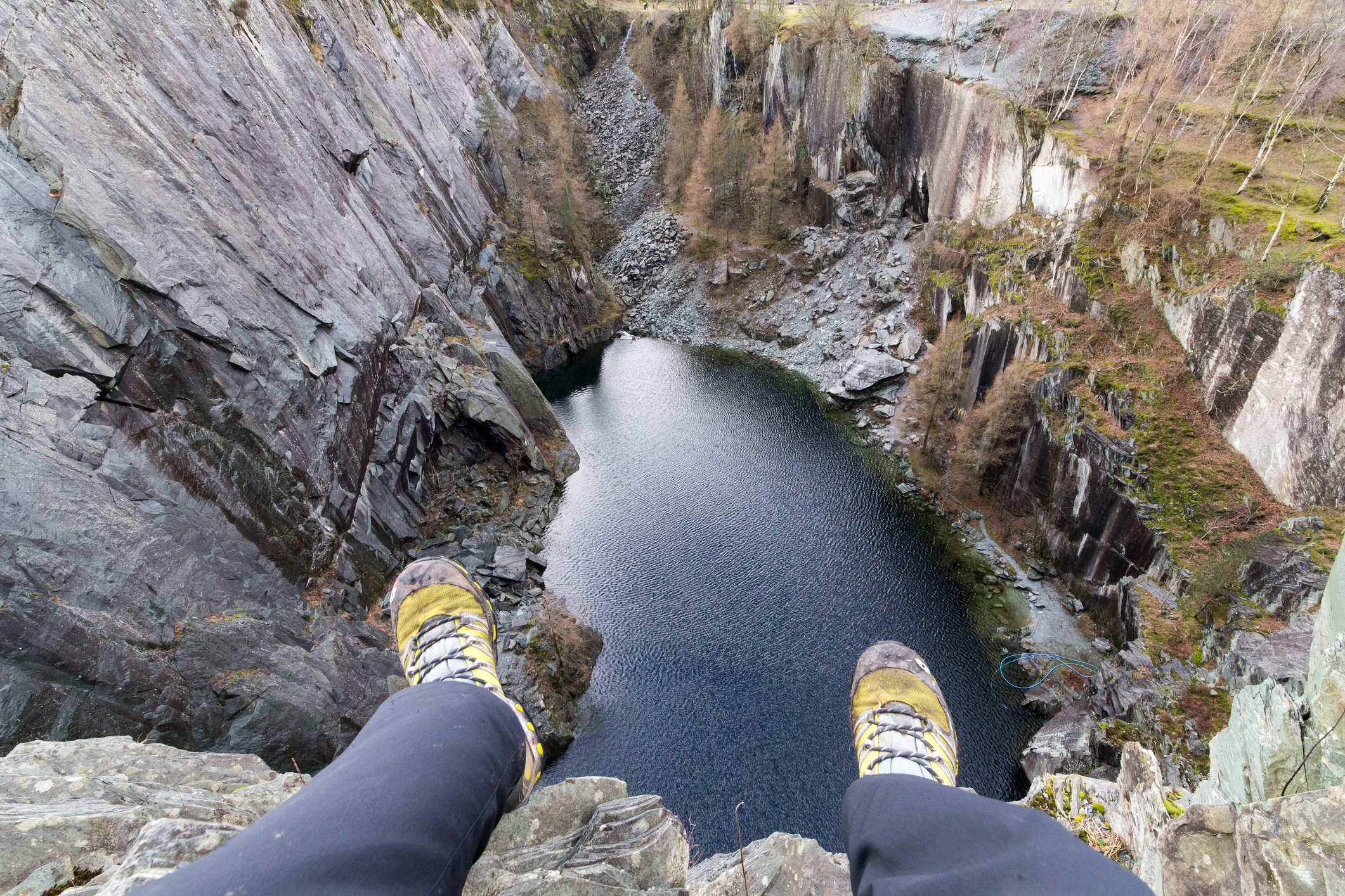 Photograph of my legs dangling over the lip of Hodge Close Quarry. An old disused Slate Quarry in the Lake District.