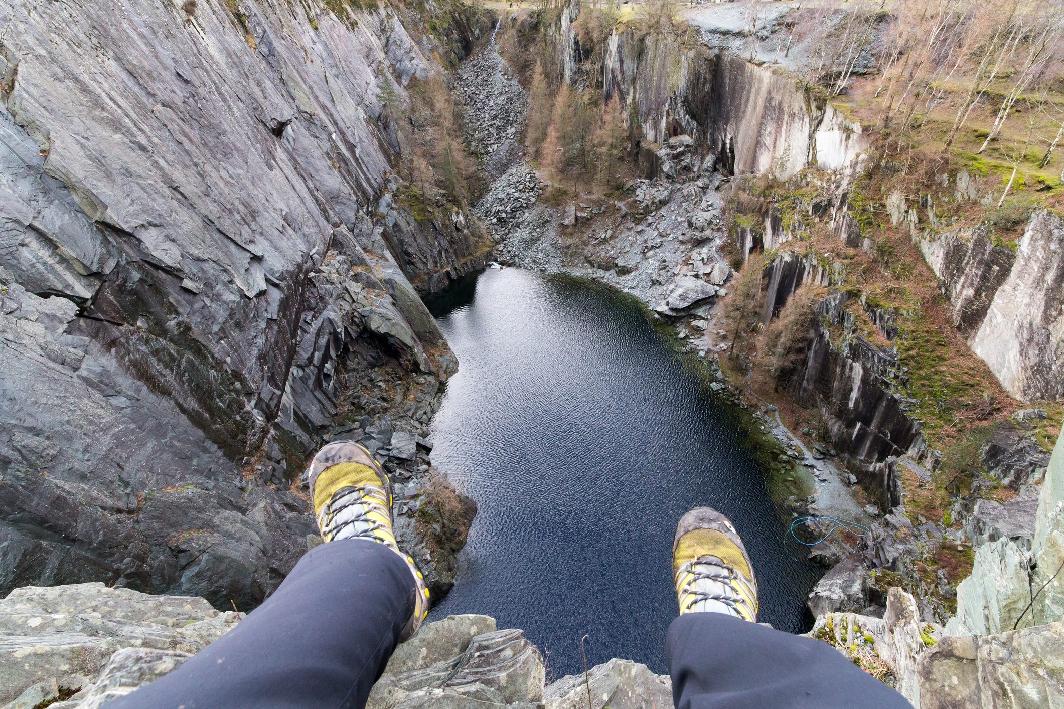 Photograph of my legs dangling over the lip of Hodge Close Quarry. An old disused Slate Quarry in the Lake District.