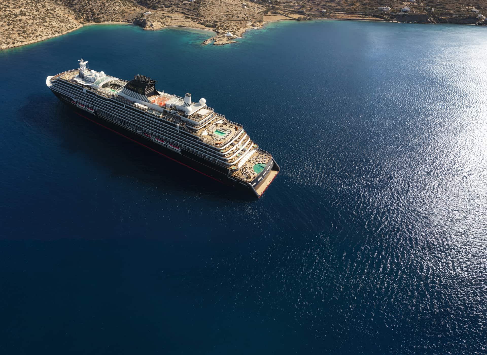 Large cruise ship in a dark blue sea by a sandy coast