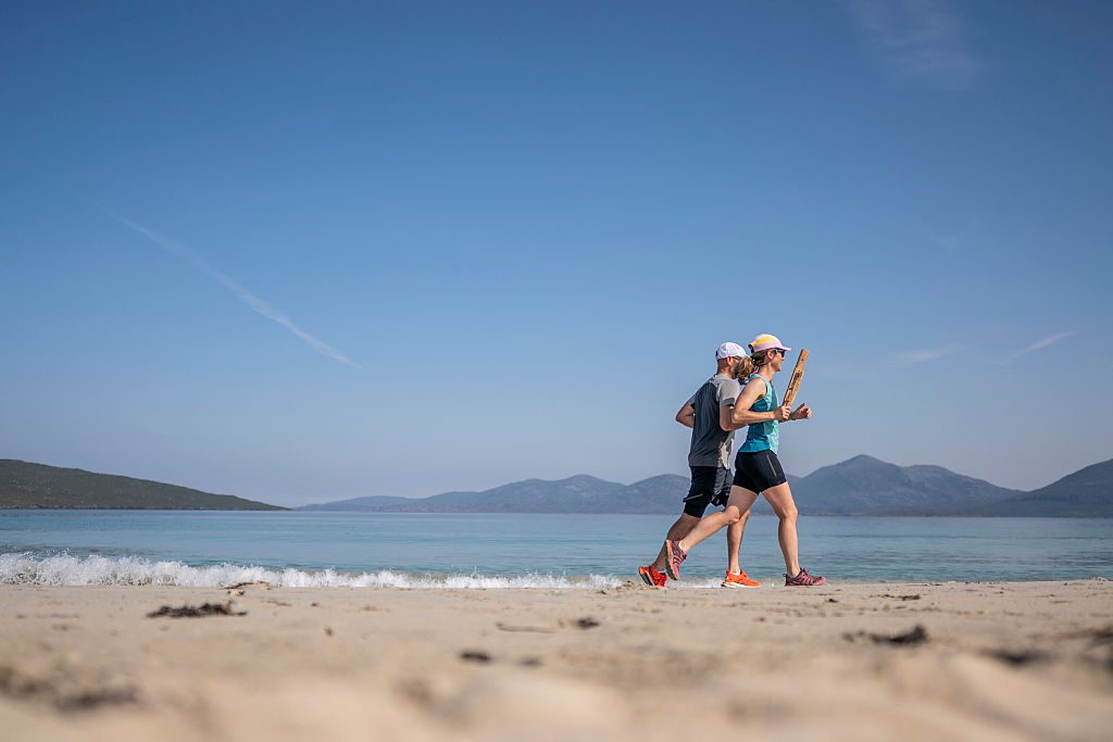 A couple run with the commonwealth baton along Luskentyre beach during the King's Baton Relay on the Isle of Harris 