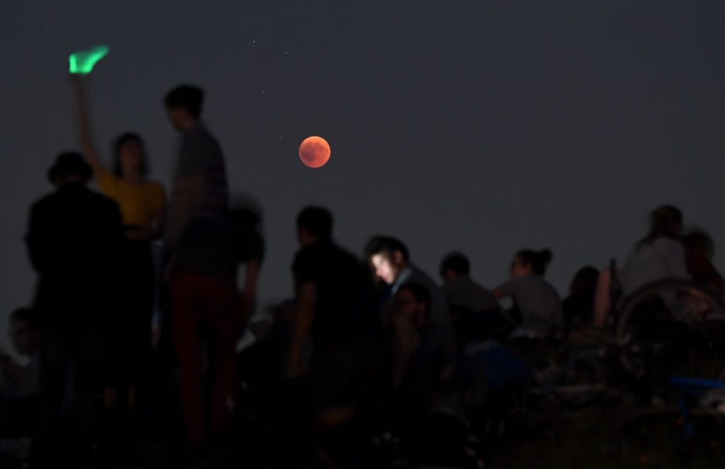 The lunar eclipse seen behind a group of people