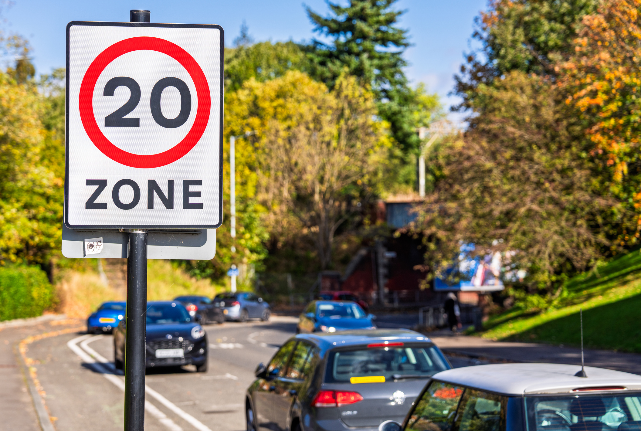 A 20mph speed sign in front of a road of cars