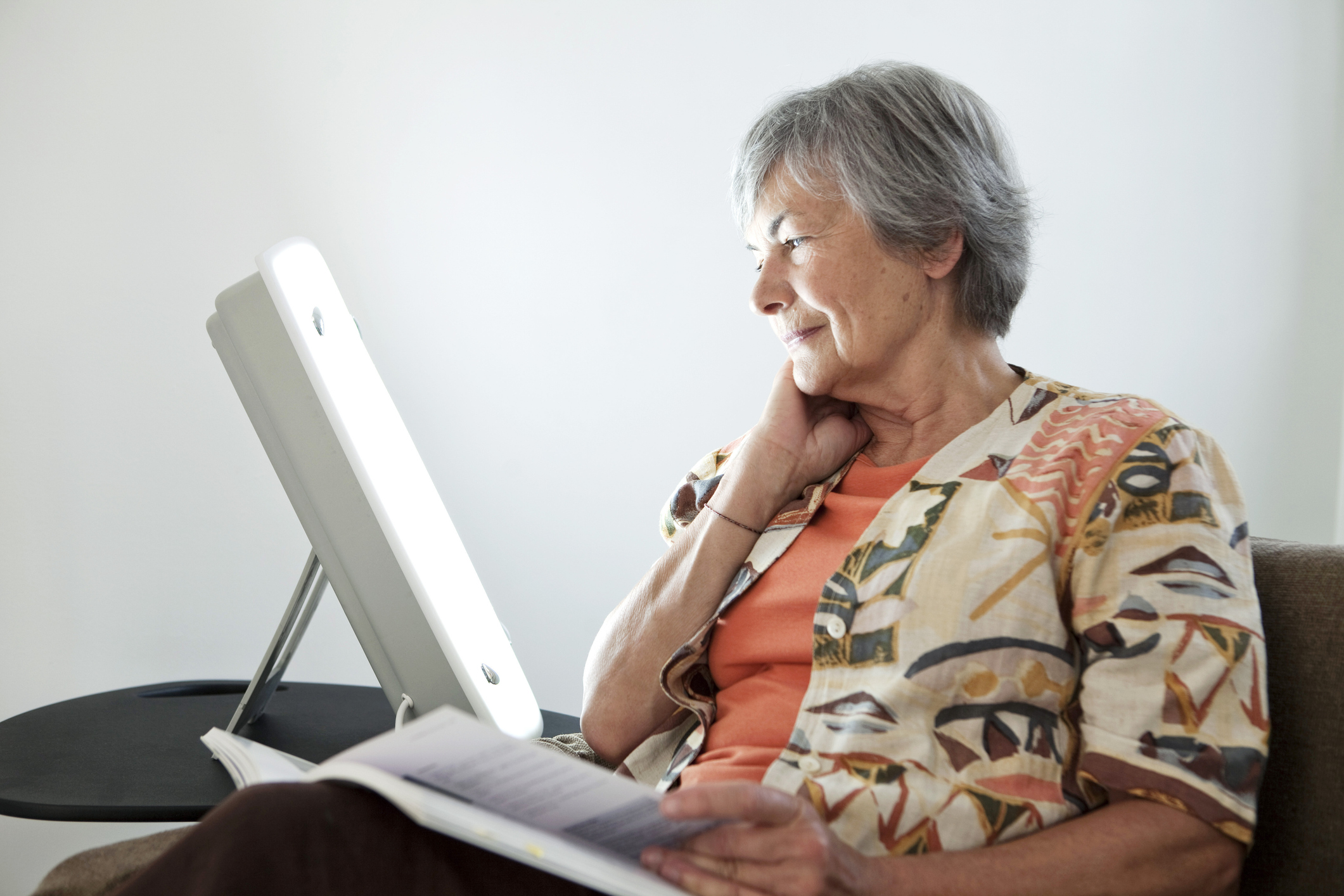 Older women looking at a light therapy machine in her home.