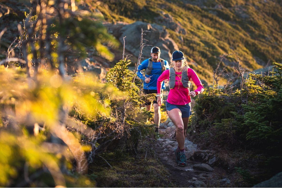 A man and woman wearing trail running gear go for a run on a dirt path